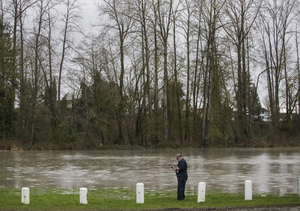 Brian Ramey stops to take a photo of the flooded Twin Rivers County Park on Saturday in Arlington. (Olivia Vanni / The Herald)
