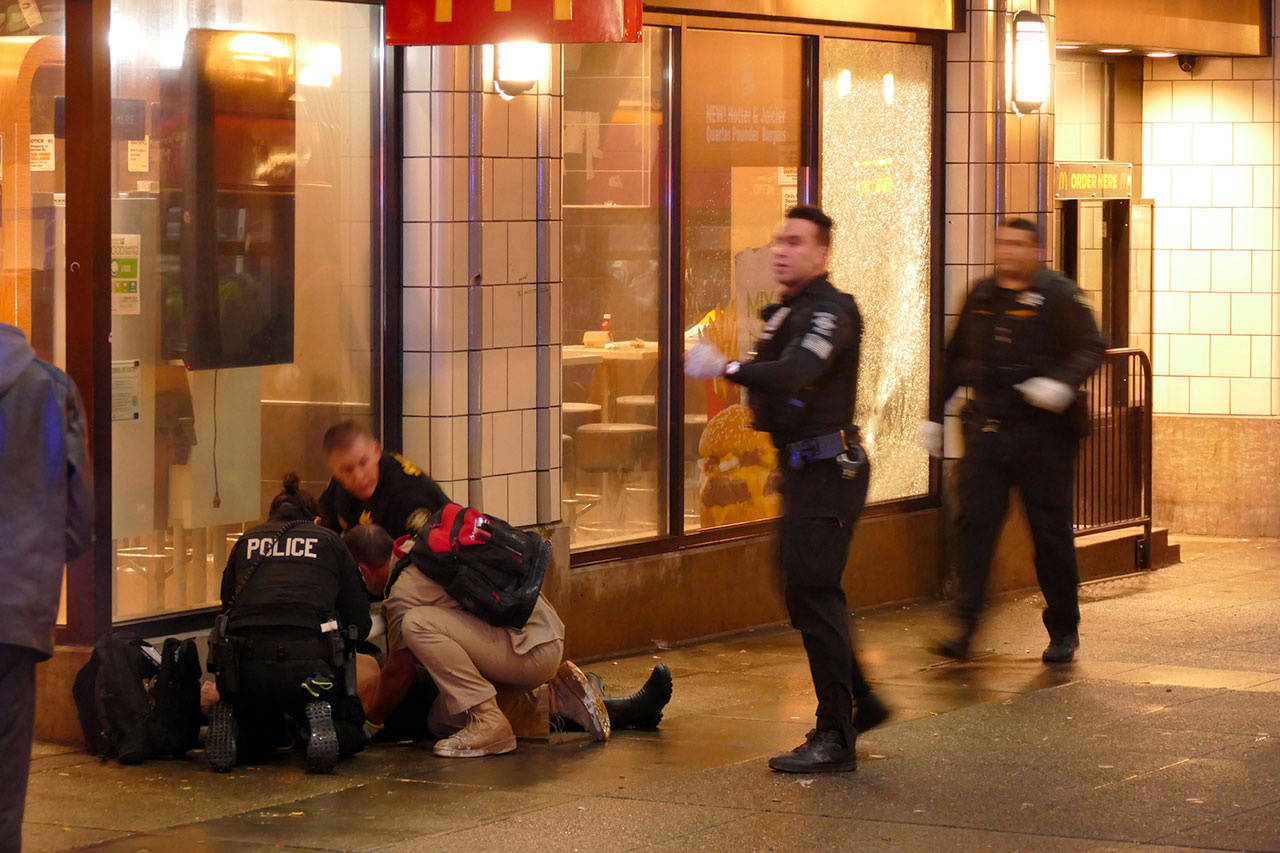 In this Jan. 22 photo, officers attend to one of several shooting victims outside of McDonald’s on Third Avenue in Seattle. (David Silver via AP, File)