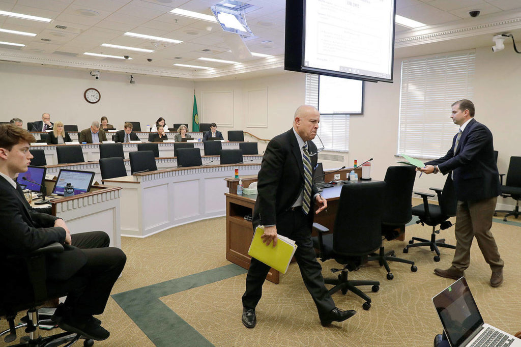 Greg Hanon (center), who represents the Western States Petroleum Association, gets up after speaking during a hearing of the state House of Representatives Environment and Energy Committee on Monday, Feb. 3 at the Capitol in Olympia. Hanon spoke in opposition to a House bill that seeks to fully reinstate Washington Gov. Jay Inslee’s plan to cap carbon pollution in Washington by giving additional regulatory authority to the state Department of Ecology. (AP Photo/Ted S. Warren) 
