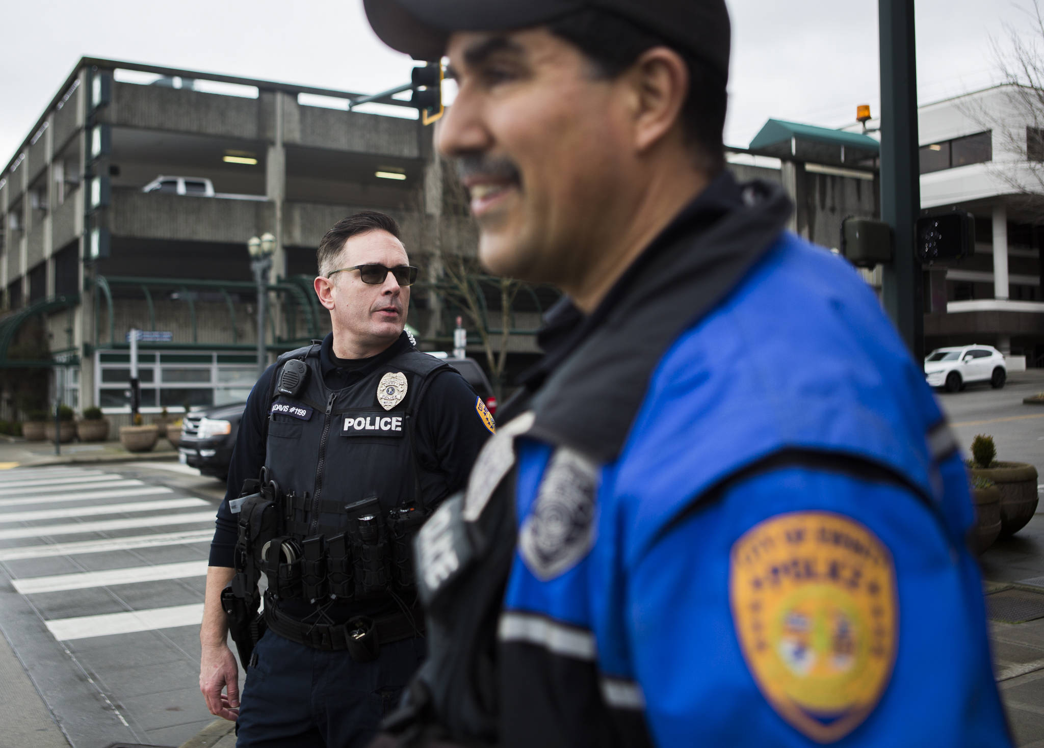 Everett Police Officers Kevin Davis (left) and Mike Bernardi wait for the light to change at the corner of Hewitt and Hoyt avenues on Thursday in downtown. Everett’s mayor and police chief plan to hire 24 additional officers by 2023 to bolster the department’s visible presence in the community. (Olivia Vanni / The Herald)