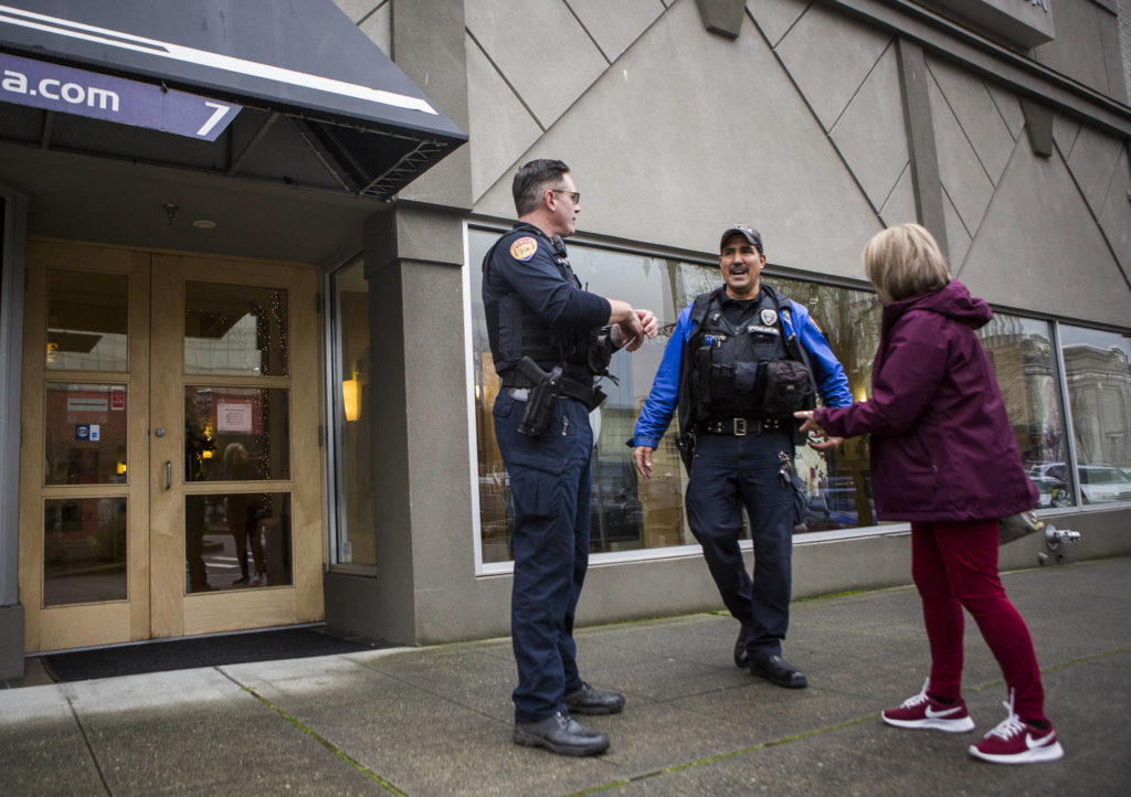 Everett Police Officers Kevin Davis (left) and Mike Bernardi chat with Kathy White as they walk through downtown Everett on Thursday. (Olivia Vanni / The Herald)
