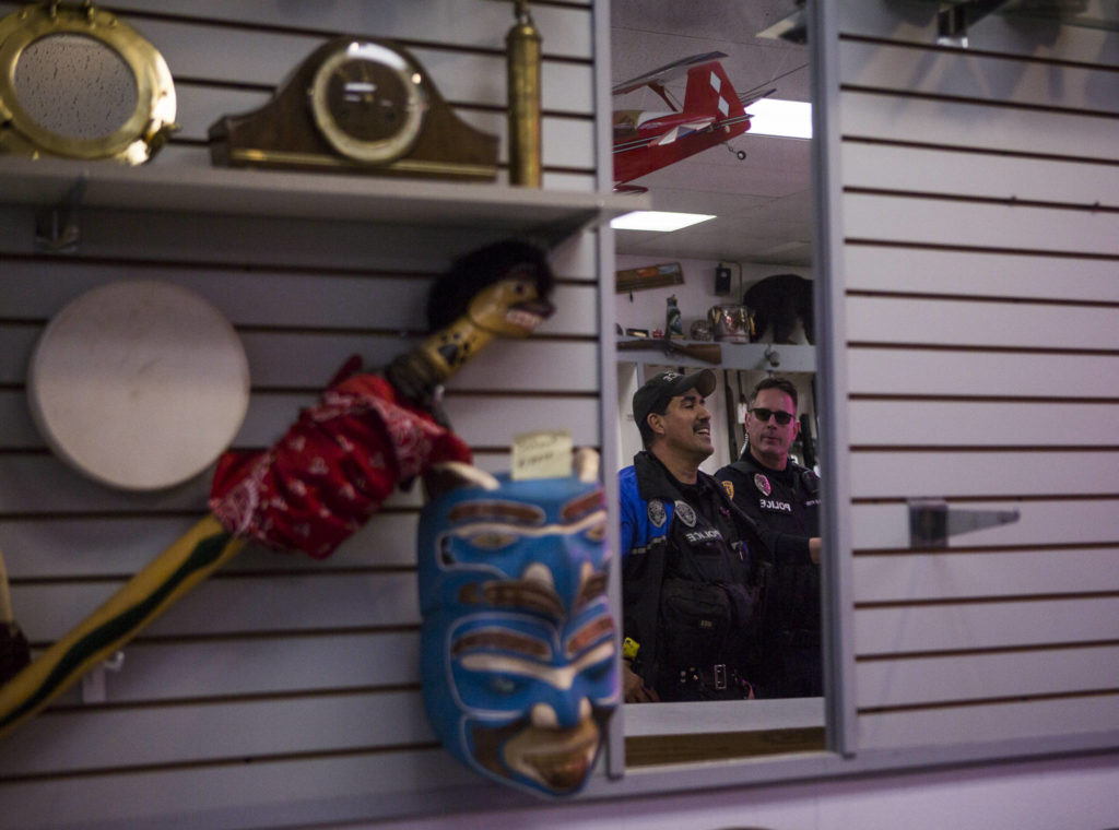 Everett Police Officers Mike Bernardi (left) and Kevin Davis chat with the owner of Sound Loan Pawn Shop, one of the businesses they visited during foot patrol downtown on Thursday. (Olivia Vanni / The Herald)
