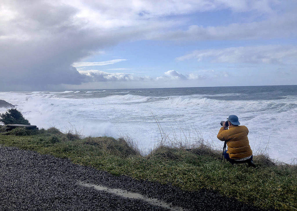 In this Jan. 11 photo, a man photographs waves crashing onto the cliffs at Rodea Point in Lincoln County, Oregon. during an extreme high tide that coincided with a big winter storm. (AP Photo/Gillian Flaccus)
