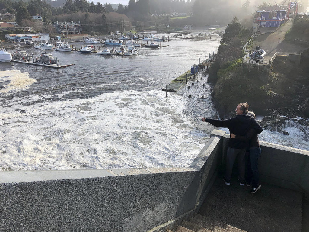 In this Jan. 11 photo, residents watch as an extreme high tide rolls in and floods parts of the harbor in Depoe Bay, Oregon during an extreme high tide that coincided with a big winter storm. (AP Photo/Gillian Flaccus)

