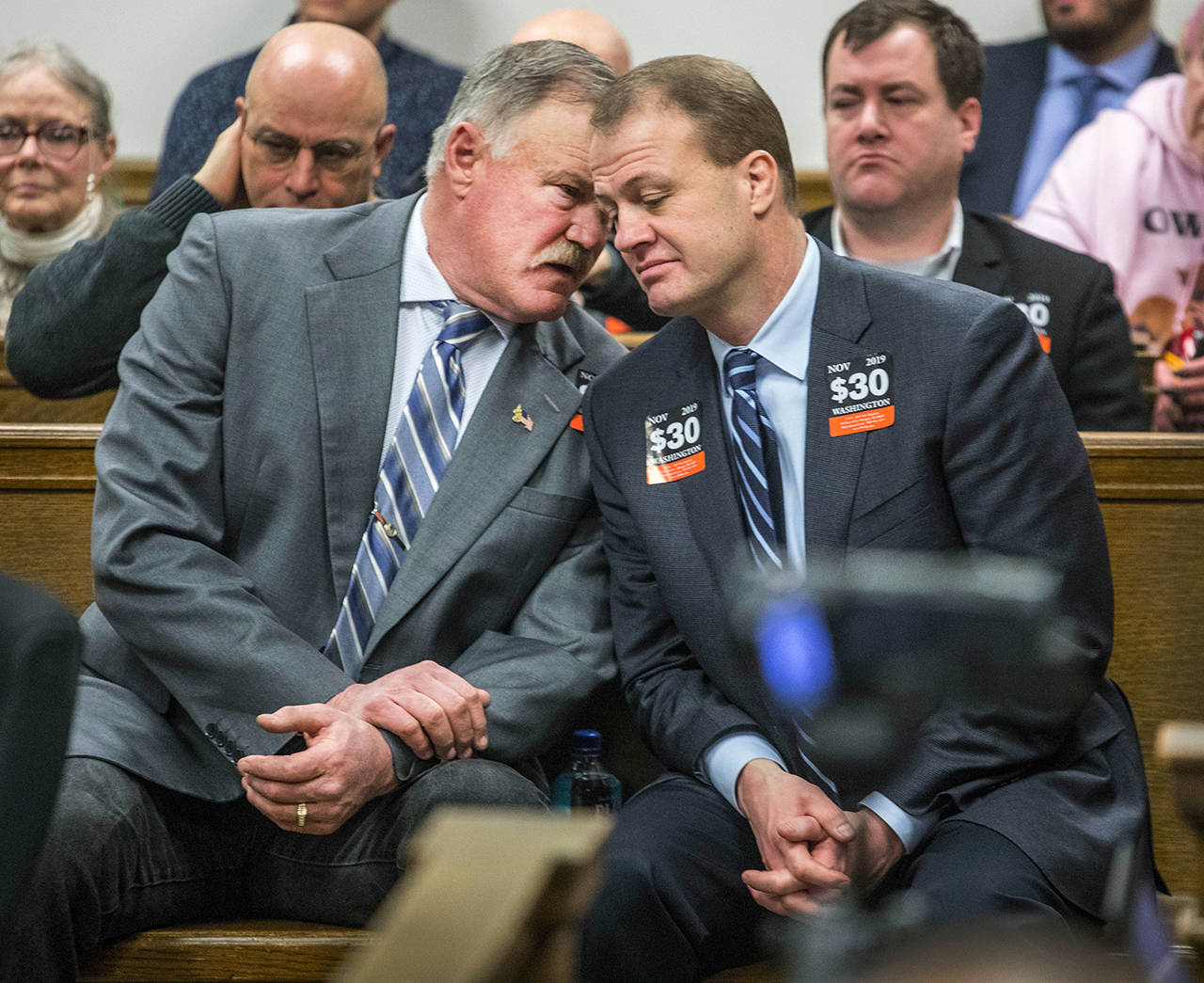 Tim Eyman (right) quietly talks with Clint Didier during the court session hearing Friday in Seattle on car-tab measure Initiative 976, which Seattle and others are suing to stop. (Steve Ringman/The Seattle Times via AP)