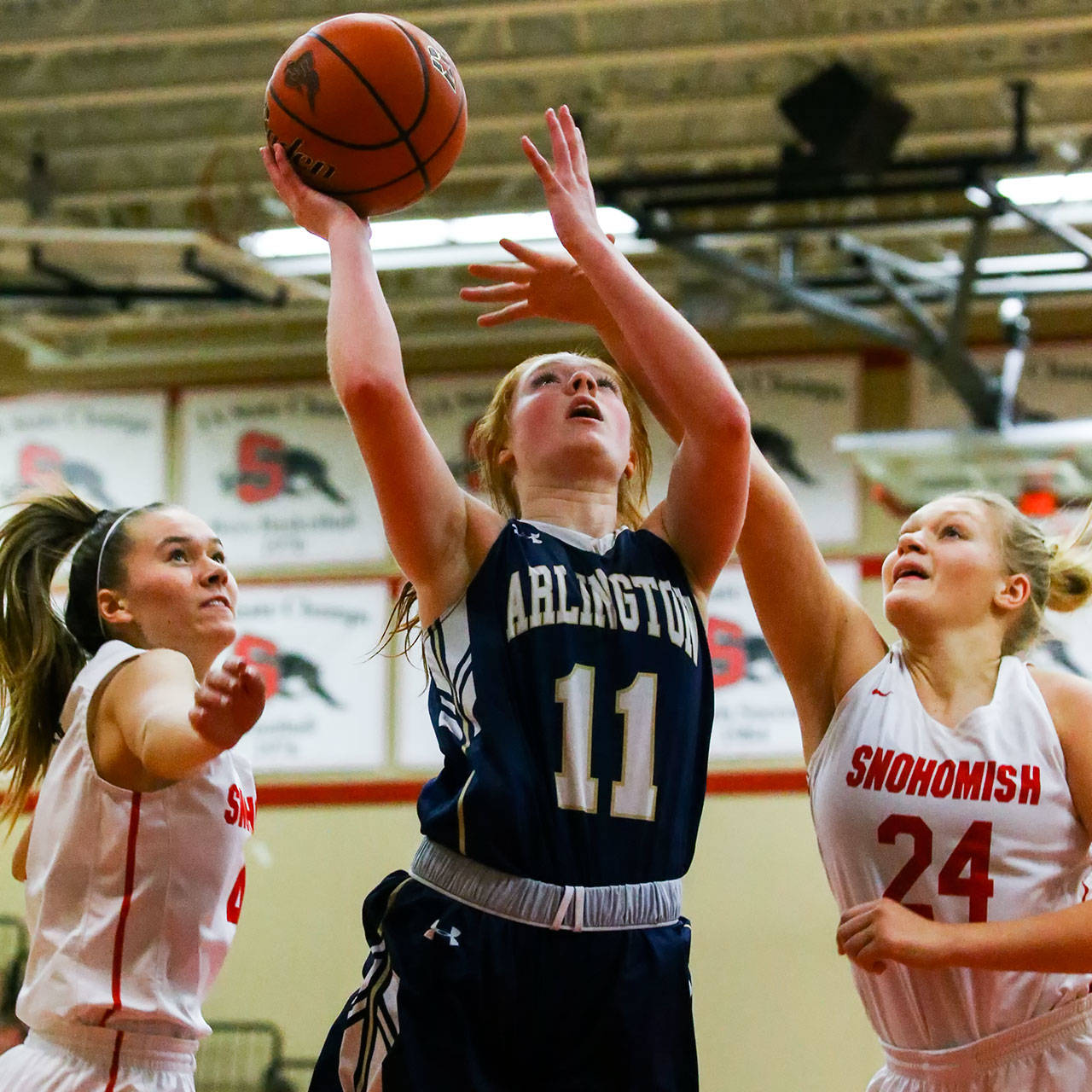 Arlington’s Makenzie Gage attempts a shot with Snohomish’s Kinslee Gallatin (left) and Kaylin Beckman defending Thursday evening at Snohomish High School in Snohomish on February 6, 2020. Arlington won 46-35. (Kevin Clark / The Herald)