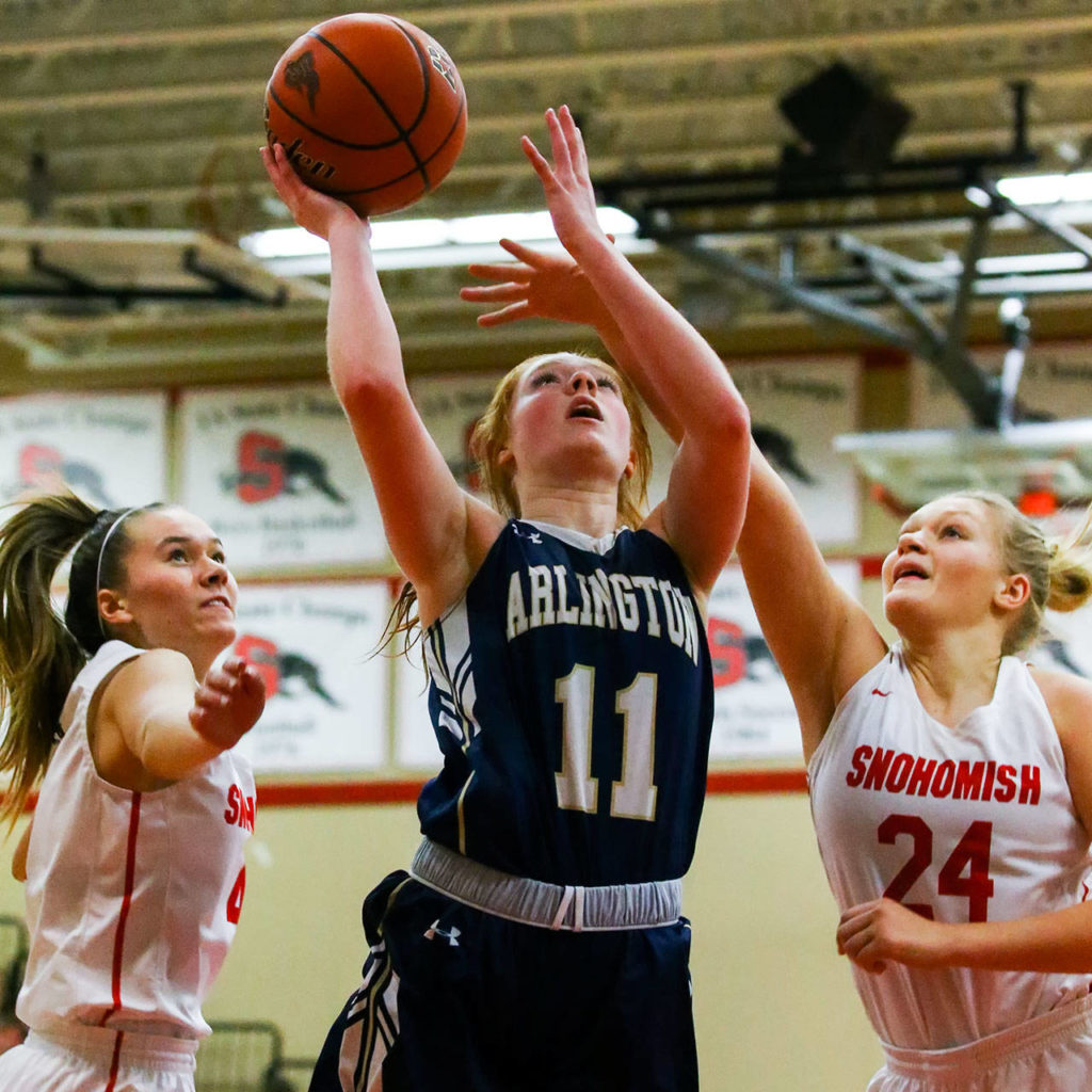 Arlington’s Makenzie Gage attempts a shot with Snohomish’s Kinslee Gallatin (left) and Kaylin Beckman defending Thursday evening at Snohomish High School in Snohomish on February 6, 2020. Arlington won 46-35. (Kevin Clark / The Herald)
