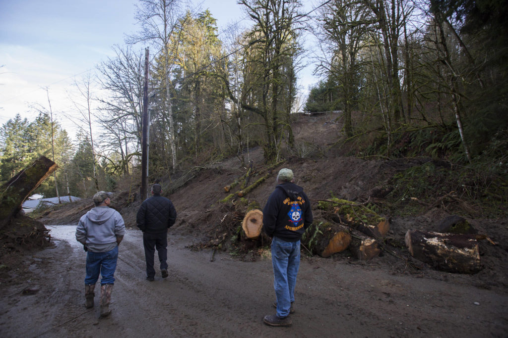 Local resident Ken Hopkins (right), who has lived at the top of the hill for 35 years, pauses to look at the slide site on Monday in Monroe. (Olivia Vanni / The Herald)
