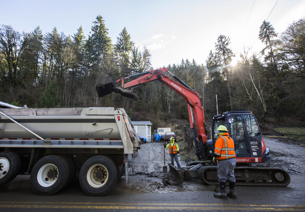 Snohomish County Public Works cleans up leftover mud from the slide Monday in Monroe. (Olivia Vanni / The Herald)
