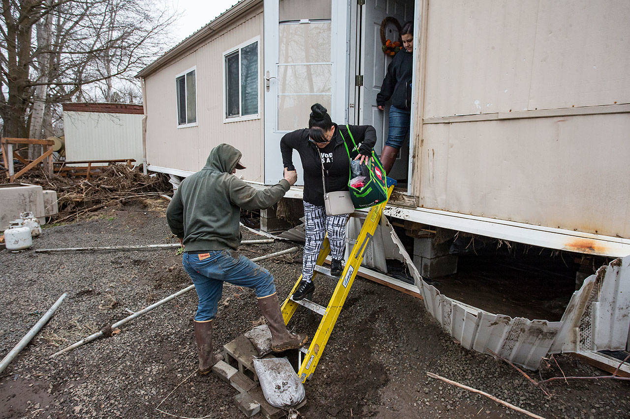 In this Feb. 8 photo, resident Patty Haid is helped from her flood-damaged home in Pendleton, Oregon. (Ben Lonergan/East Oregonian via AP)