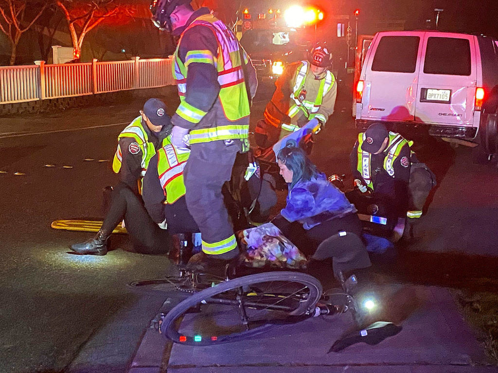 Emergency responders tend to a woman, 48, who was injured Monday night after a van hit her while riding her bike on 176th Street SW. near 60th Avenue W., in Lynnwood. (Lynnwood Police Department)
