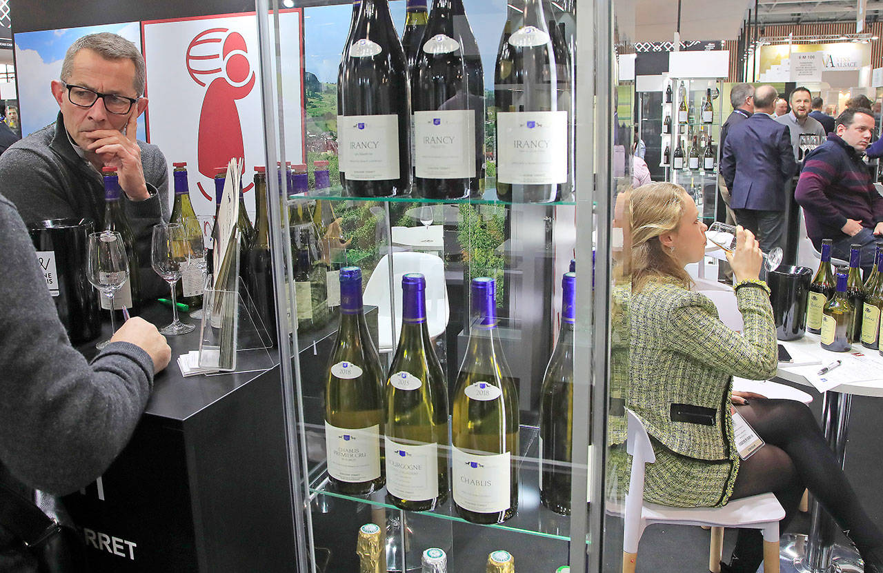 Wine fairgoers taste wines of the Burgundy region in Paris on Feb. 10, 2020. Two thousand winemakers — including giant Moet-Hennessy— are wooing some 30,000 French and international visitors at the Vinexpo fair with a renewed focus on ecology and sustainability as well as tech innovation like robots. (AP Photo/Michel Euler)
