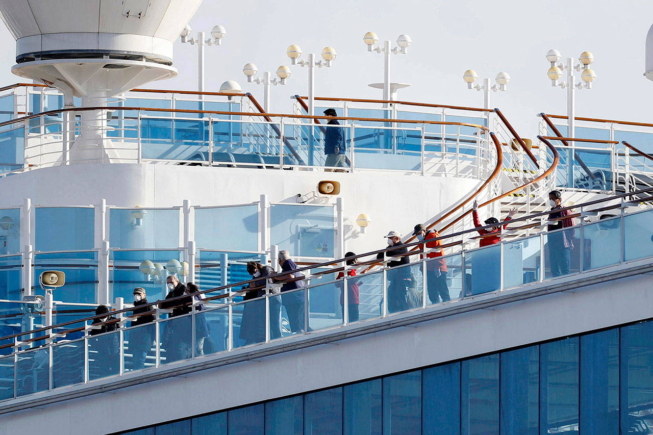 Passengers stand on the deck of the Diamond Princess cruise ship anchored at Yokohama Port in Yokohama, near Tokyo, on Wednesday. (Yuta Omori/Kyodo News via AP)