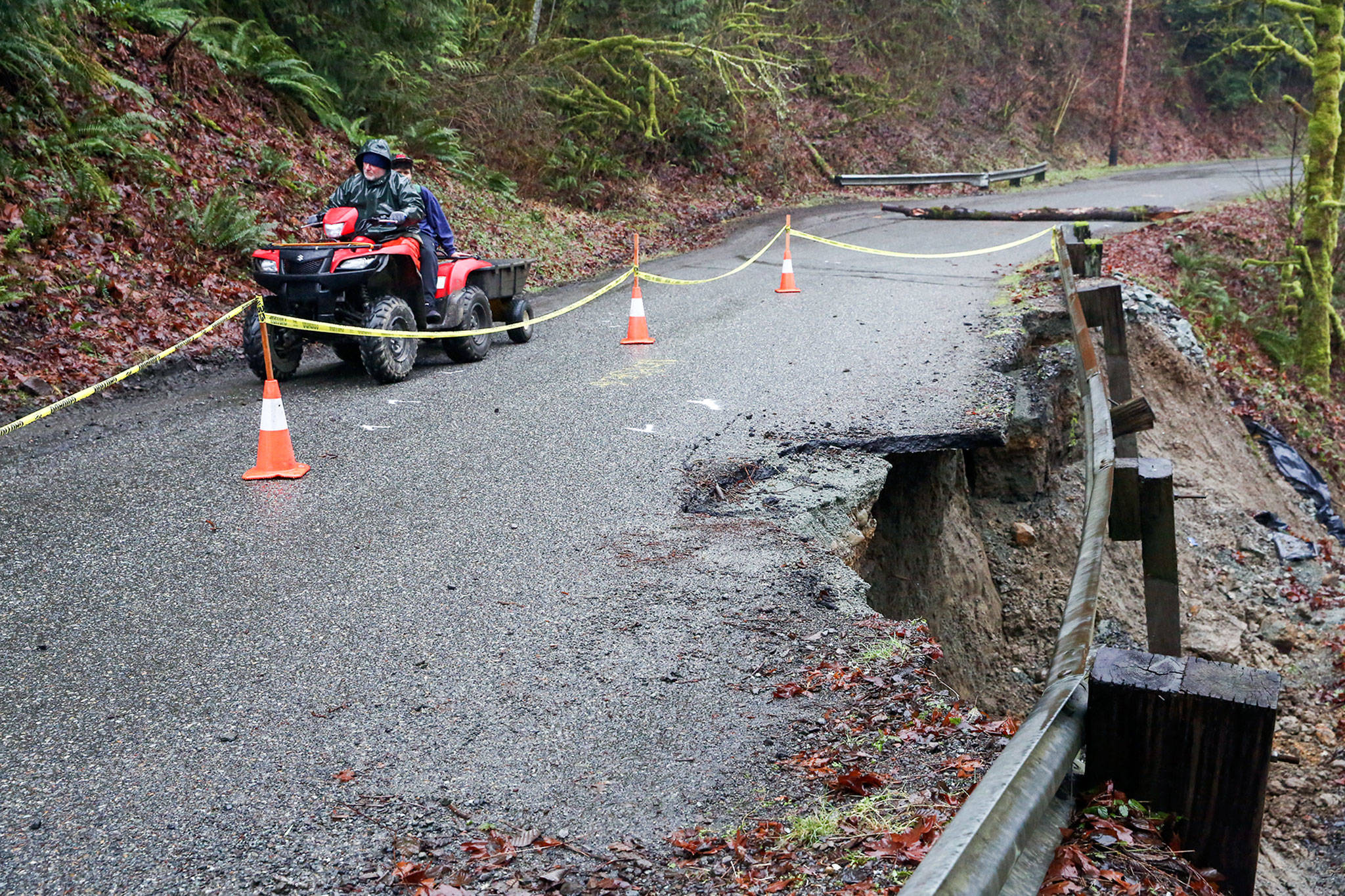 A resident uses an ATV to navigate the washed out and crumbling road bed of 260th Ave NE leading to Skyview Estate in Monroe on February 13, 2020. (Kevin Clark / The Herald)
