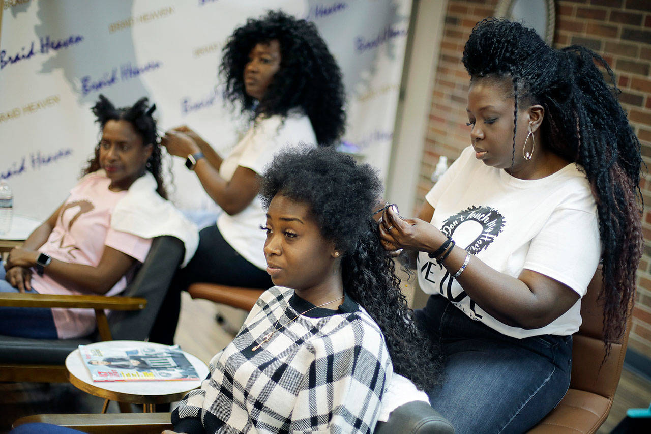 Sisters Shelly Smith (back) and Glynnis Smith (right) braid hair for Bridget Dunmore (left) and Alicia McGee (front) at their salon, Braid Heaven, on Jan. 28 in Kansas City, Kansas. Legislators in Kansas and Wisconsin are considering whether to revise their states’ anti-discrimination laws to ban bias in housing, employment and public accommodations based on hairstyles “historically associated with race” such as braids, locs and twists. (AP Photo/Charlie Riedel)