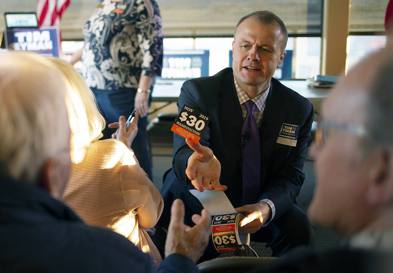 Tim Eyman hands out $30 car tab stickers while greeting supporters before officially announcing his campaign to run for governor of Washington as a Republican on Wednesday in Yakima. (Evan Abell/Yakima Herald-Republic via AP)