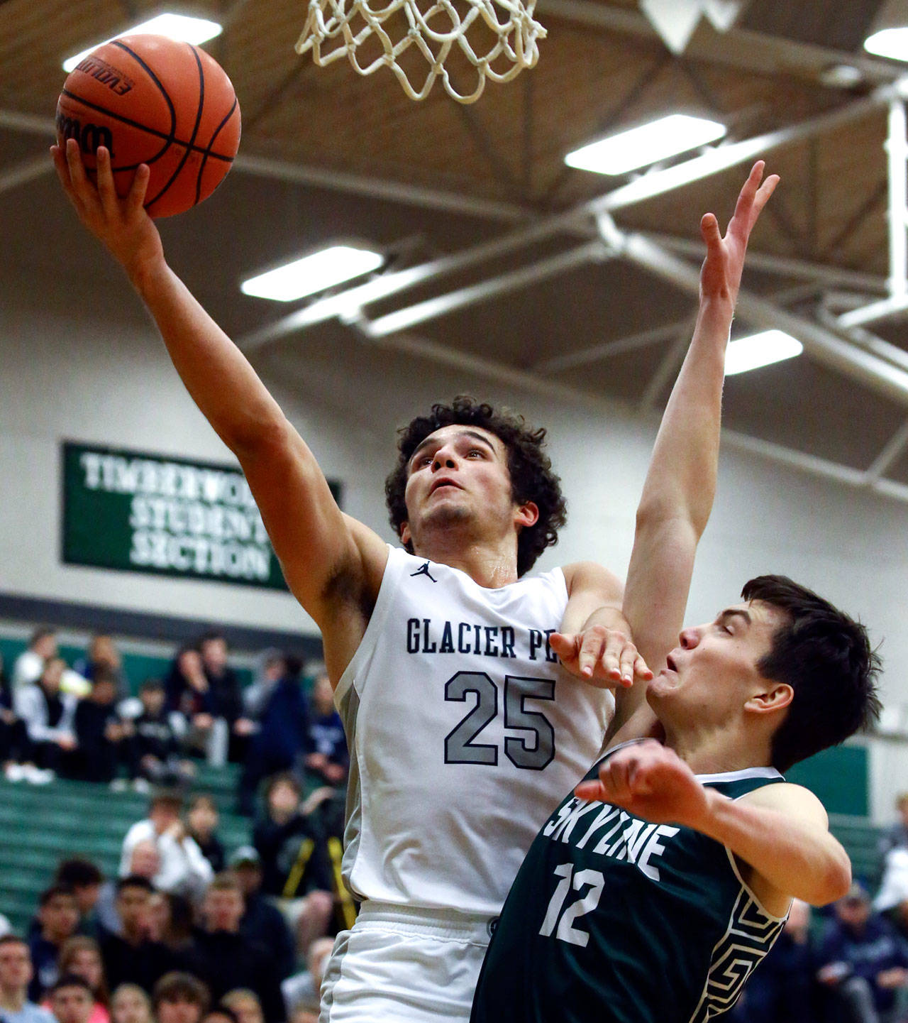Glacier Peak’s Brayden Quantrille (25) drives for a layup with Skyline’s Zach Ulmer trailing during a Wes-King Bi-District Tournament game Tuesday evening at Jackson High School in Mill Creek. (Kevin Clark / The Herald)