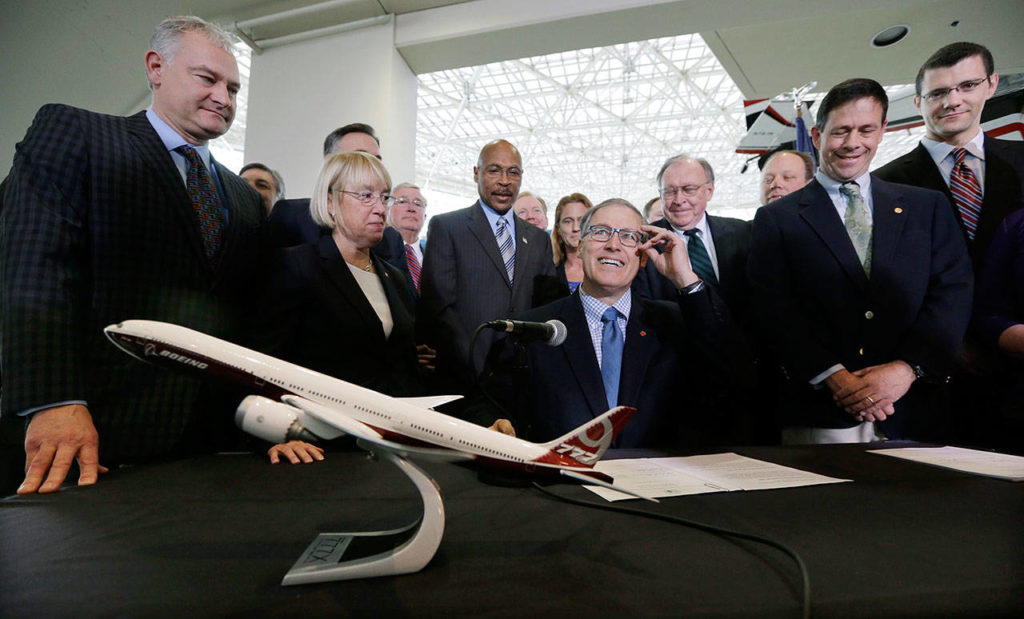 On Nov. 11, 2013, Gov. Jay Inslee (center) looks up during a signing event at the Museum of Flight in Seattle for legislation to help keep production of Boeing’s new 777X airplane in Washington. (AP Photo/Elaine Thompson, File) 
