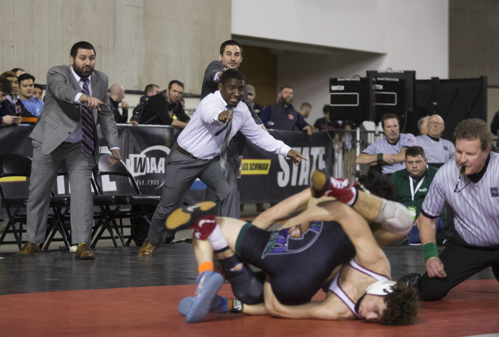 Edmonds-Woodway coaches cheer on Warriors sophomore Alex Rapelje (top) in his 138-pound title match against Prairie’s Jacon Wilcox during Mat Classic XXXII in the Tacoma Dome on Saturday. (Andy Bronson / The Herald)
