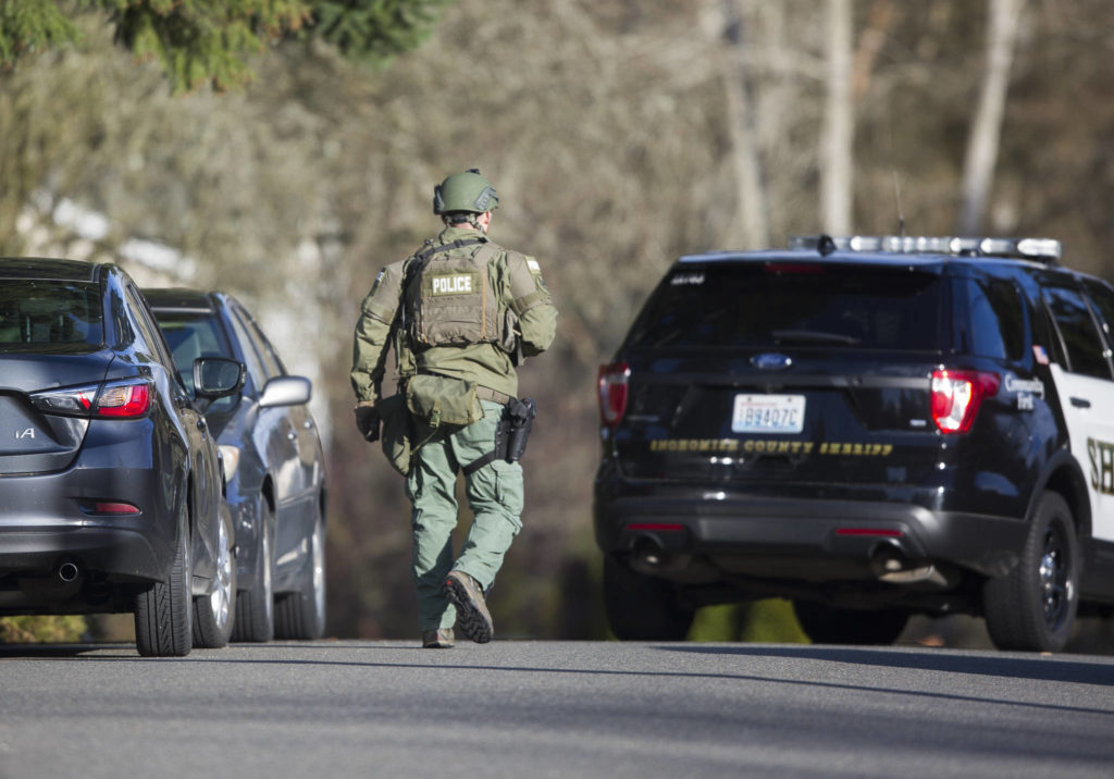 A police officer makes his way down 163rd Place SW on Sunday near Lynnwood. (Olivia Vanni / The Herald)
