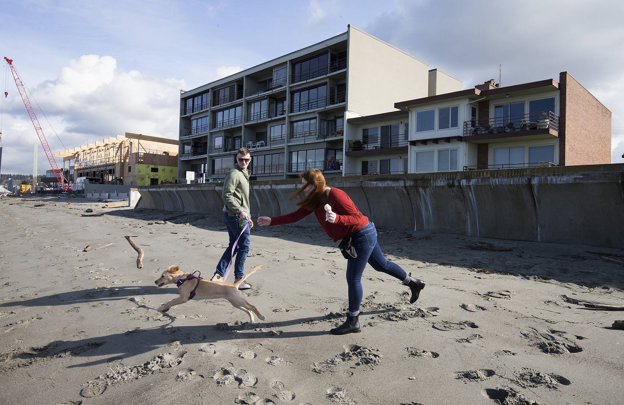 Andrea Lynch throws a stick for Willow, as Andrew Dorchak watches, during a walk on the beach along the Edmonds the waterfront on Wednesday. (Andy Bronson / The Herald)