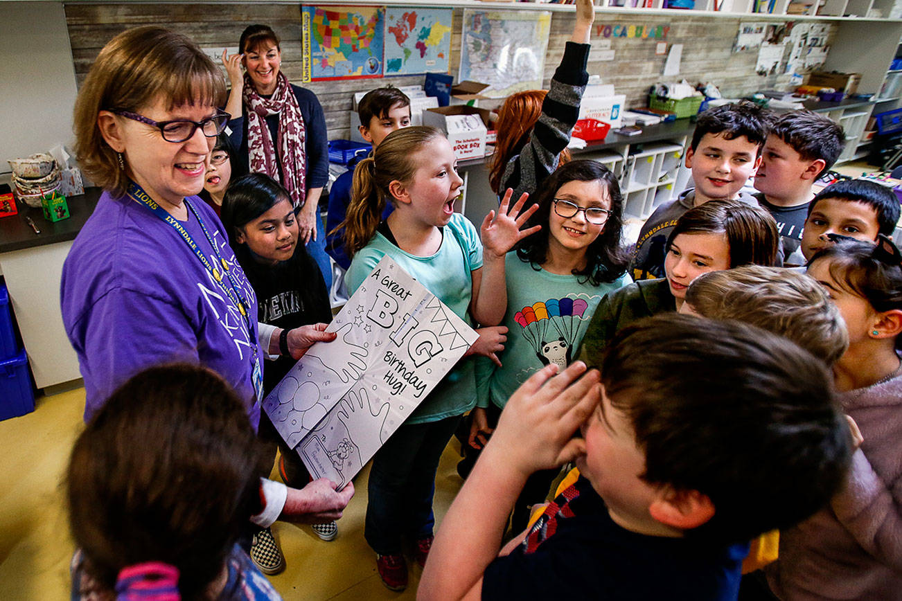 Dan Bates / The Herald                                Diane Grossenbacher, office manager at Lynndale Elementary School, will celebrate her 15th actual birthday and turn 60 on Saturday, leap day. Third- and fourth-graders on Wednesday give her an early birthday card and had fun answering math questions related to leap year.