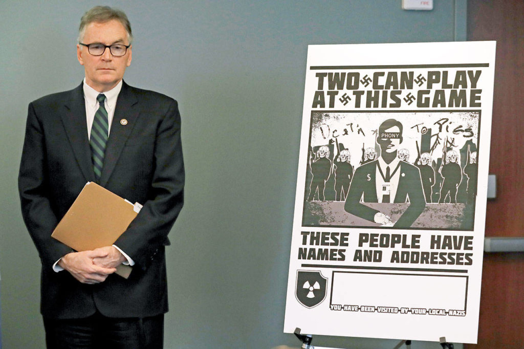 Ted S. Warren / Associated Press
At a news conference in Seattle Wednesday, U.S. Attorney Brian Moran stands next to a poster that was mailed earlier this year to the home of Chris Ingalls, a reporter with KING-TV. Moran and other officials announced charges against members of a neo-Nazi group called Atomwaffen Division, who are accused of cyber-stalking and mailing threatening communications.
