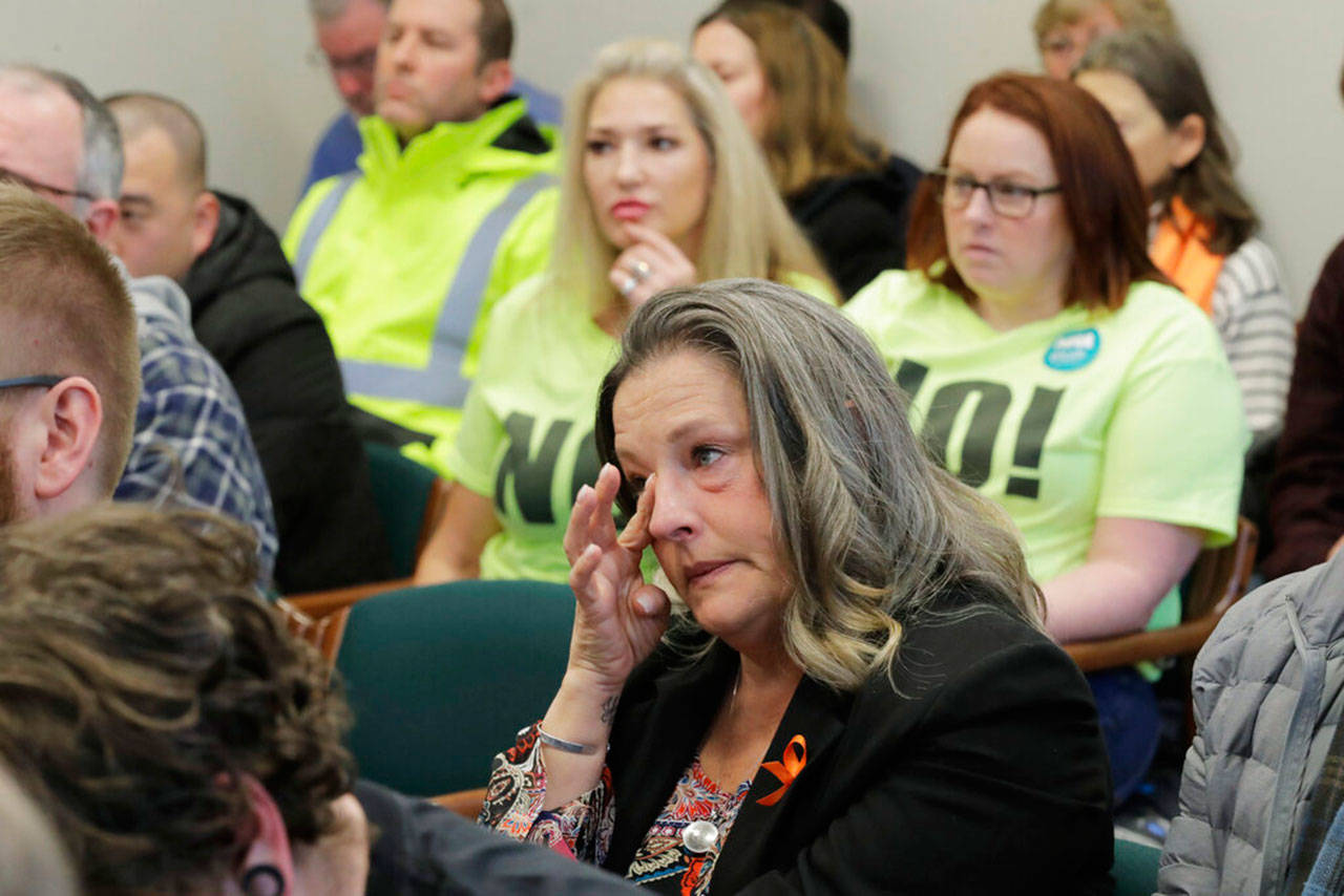 Ami Strahan (center), whose son Sam, 15, was shot and killed in 2017 during a shooting at Freeman High School in Rockford, wipes her eye as she listens to testimony, Tuesda at a public hearing at the Capitol in Olympia, on a new bill that would ban high-capacity gun magazines in Washington state. Strahan, who is sitting near opponents of the measure wearing T-shirts that read “No!” spoke in support of the bill. (Ted S. Warren / Associated Press)