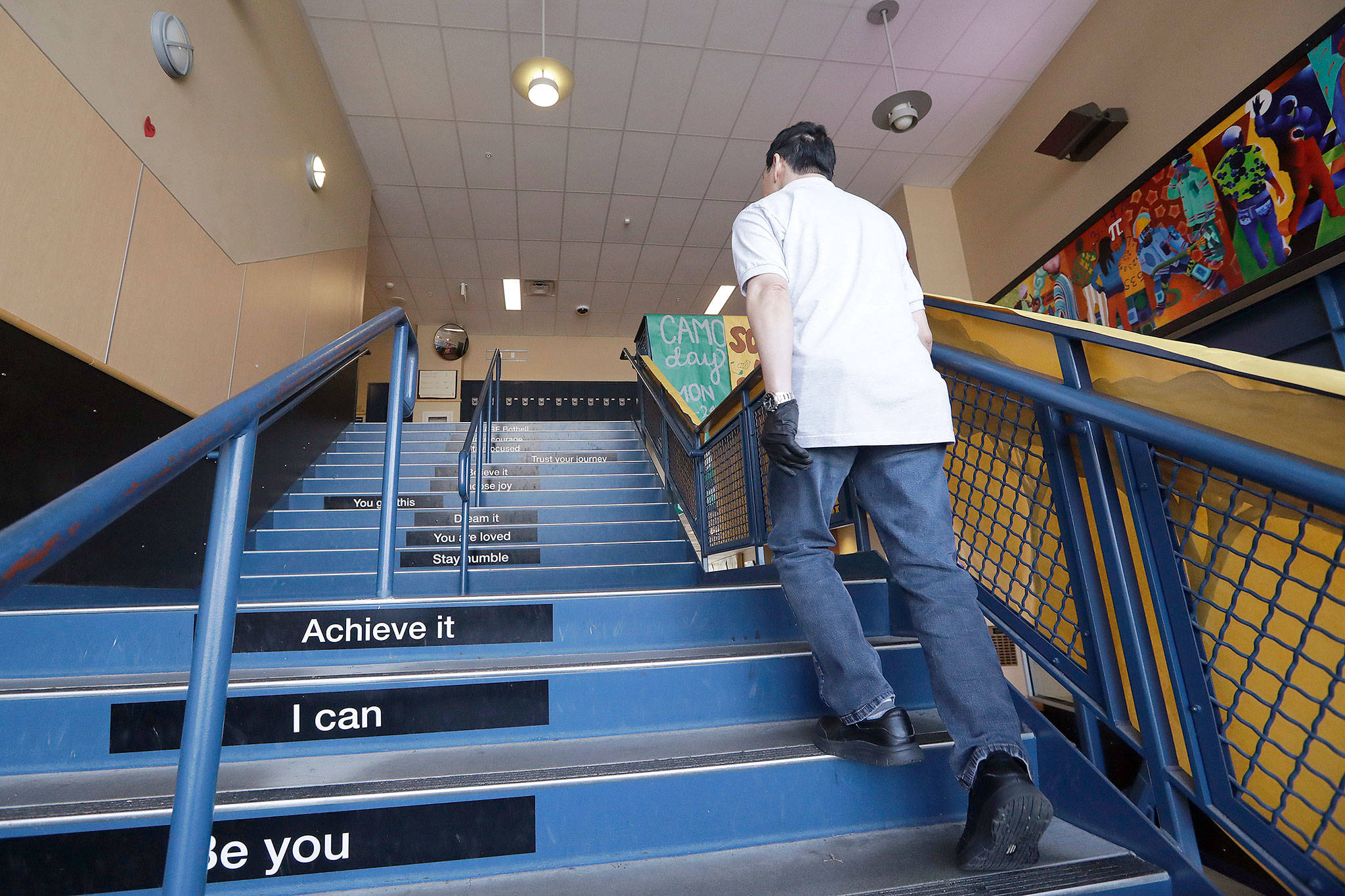 A school janitor walks up stairs inside Bothell High School, which was closed Thursday and Friday after a staffer’s family member was placed in quarantine for showing symptoms of possibly contracting the new coronavirus. The school was cleaned and disinfected, and the family member tested negative for COVID-19. (AP Photo/Elaine Thompson)