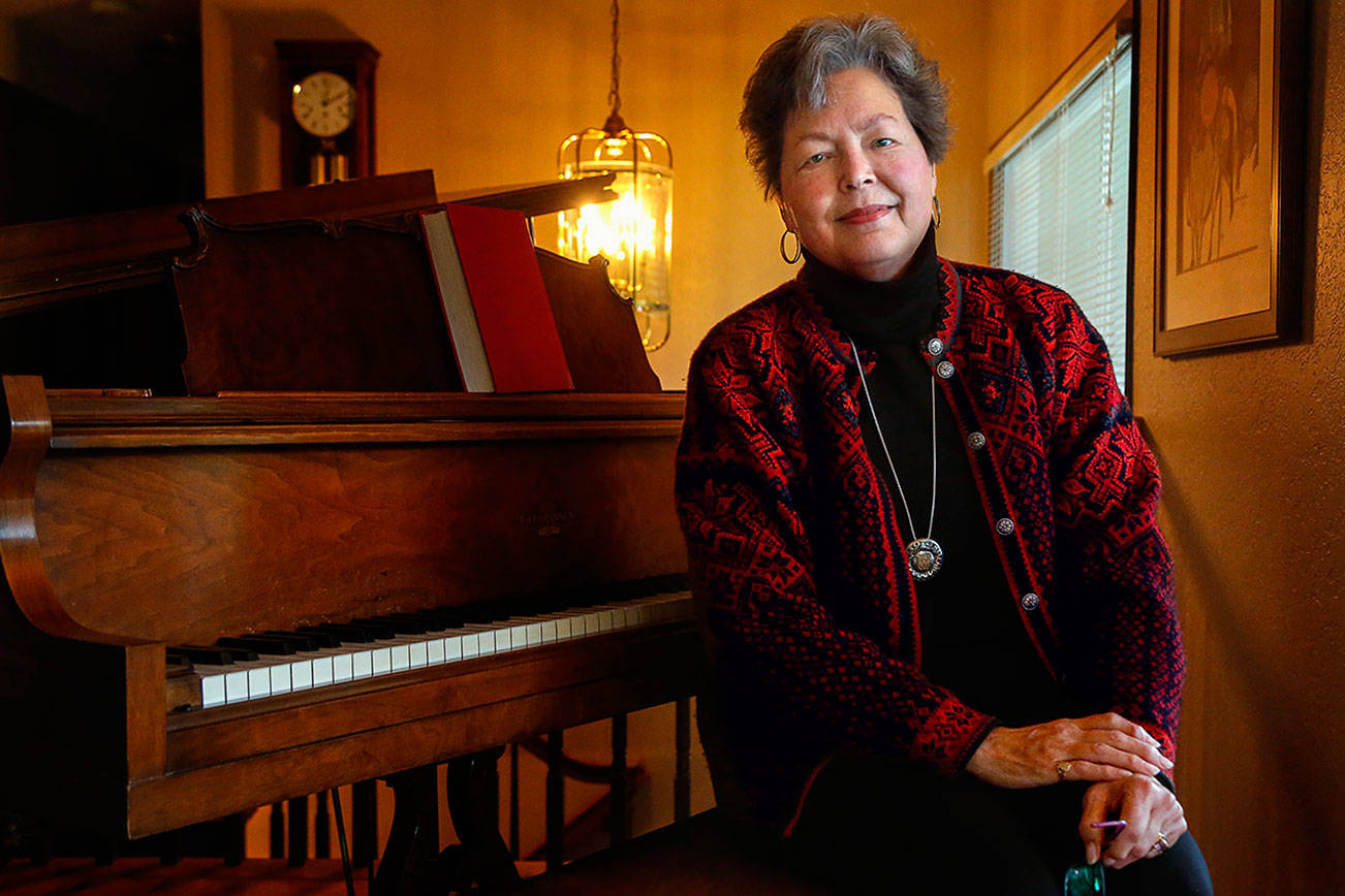 At home in Edmonds, Catherine Fransson talks about her memoir “Loving the Enemy,” which centers on her relationship with her late father. A retired high school teacher and pastor, she is also a classical pianist. (Dan Bates / The Herald)