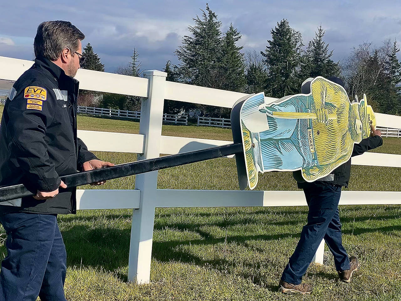 Camano Island Fire Rescue Fire department workers Jay Jacks (left) and Jake Schorzman carry Smokey Bear to install by the fire danger warning sign on Highway 532. The metal bear is a hand-me-down from the state Department of Natural Resources. (Andrea Brown / The Herald)