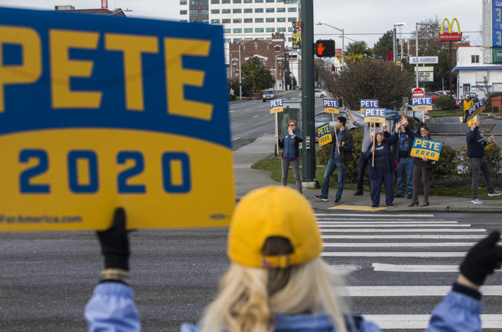 Everett Mayor Cassie Franklin and other Pete Buttigieg supporters wave at passing cars on the corner of Everett Avenue and Broadway on Feb. 29 in Everett. (Olivia Vanni / The Herald)
