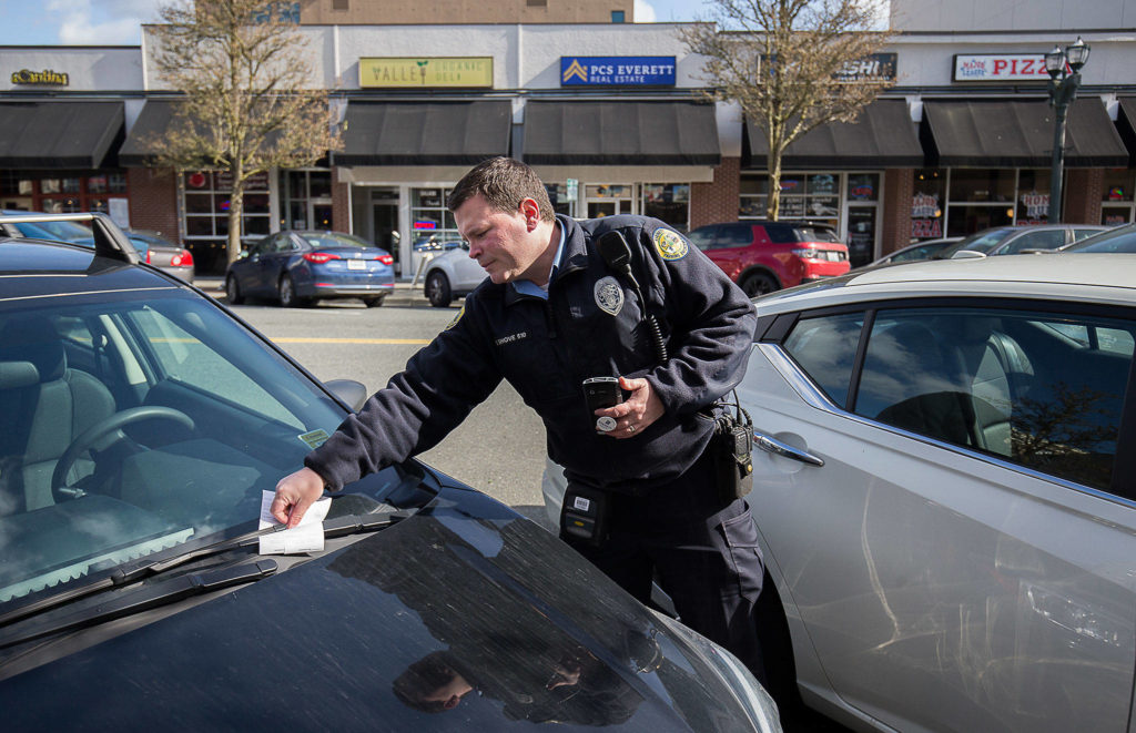 Everett parking enforcement officer Donny Shove puts a ticket on a vehicle for parking over 90 minutes on Colby Avenue on Wednesday in Everett. (Andy Bronson / The Herald)
