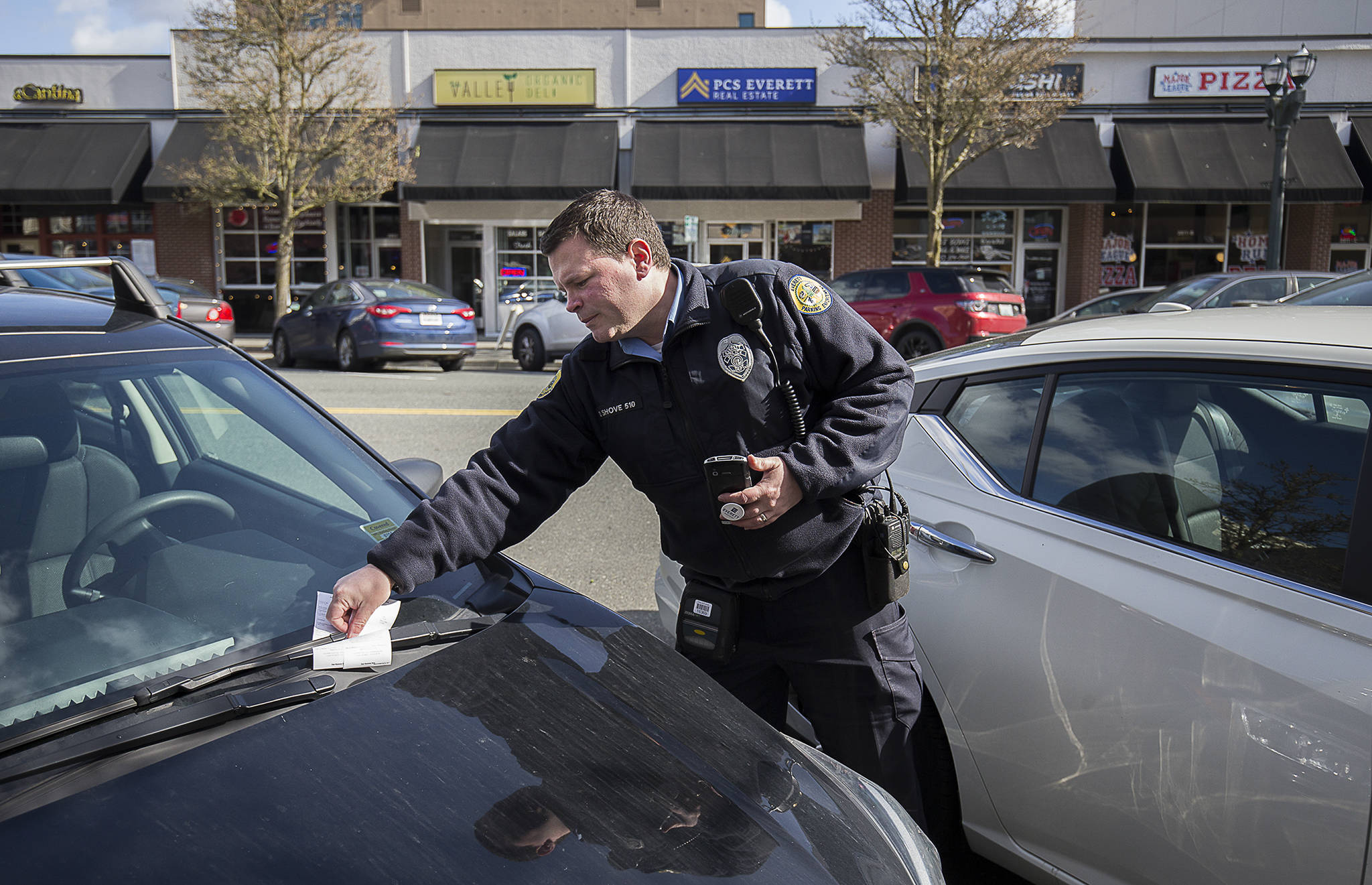 Everett parking enforcement officer Donny Shove puts a ticket on a vehicle for parking over 90 minutes on Colby Avenue on Wednesday in Everett. (Andy Bronson / The Herald)