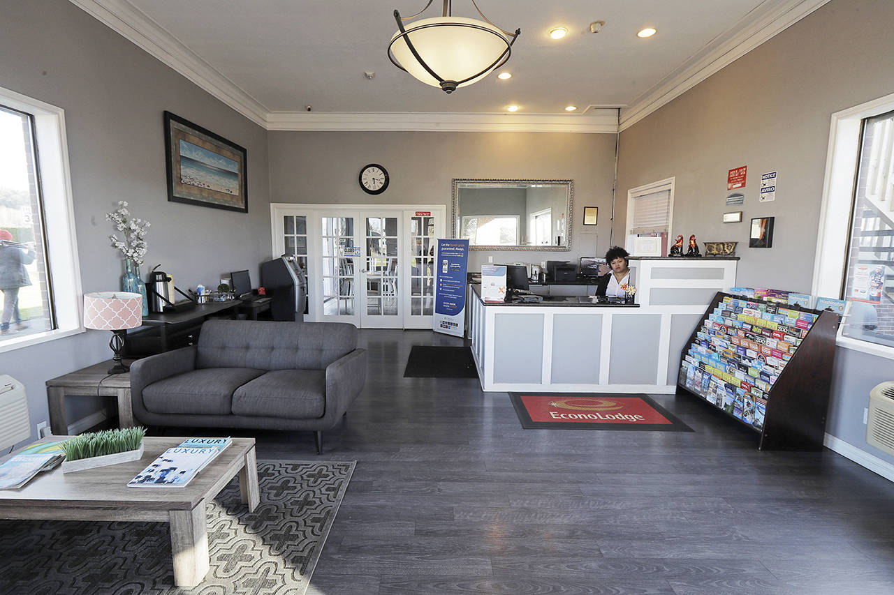 A clerk staffs the front desk of an Econo Lodge motel in Kent on Wednesday. King County Executive Dow Constantine said that the county had purchased the 85-bed motel — which is currently open and operating — south of Seattle to house patients for recovery and isolation due to the COVID-19 coronavirus. (AP Photo/Ted S. Warren)