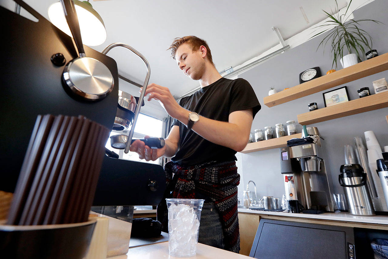 Barista Porter Hahn makes an iced drink for a customer in a coffee shop in Seattle in November. U.S. services companies grew at a faster pace in February 2020 than the previous month, an indication that the economy is still expanding, despite growing concerns about the global coronavirus outbreak. (AP Photo/Elaine Thompson, File)