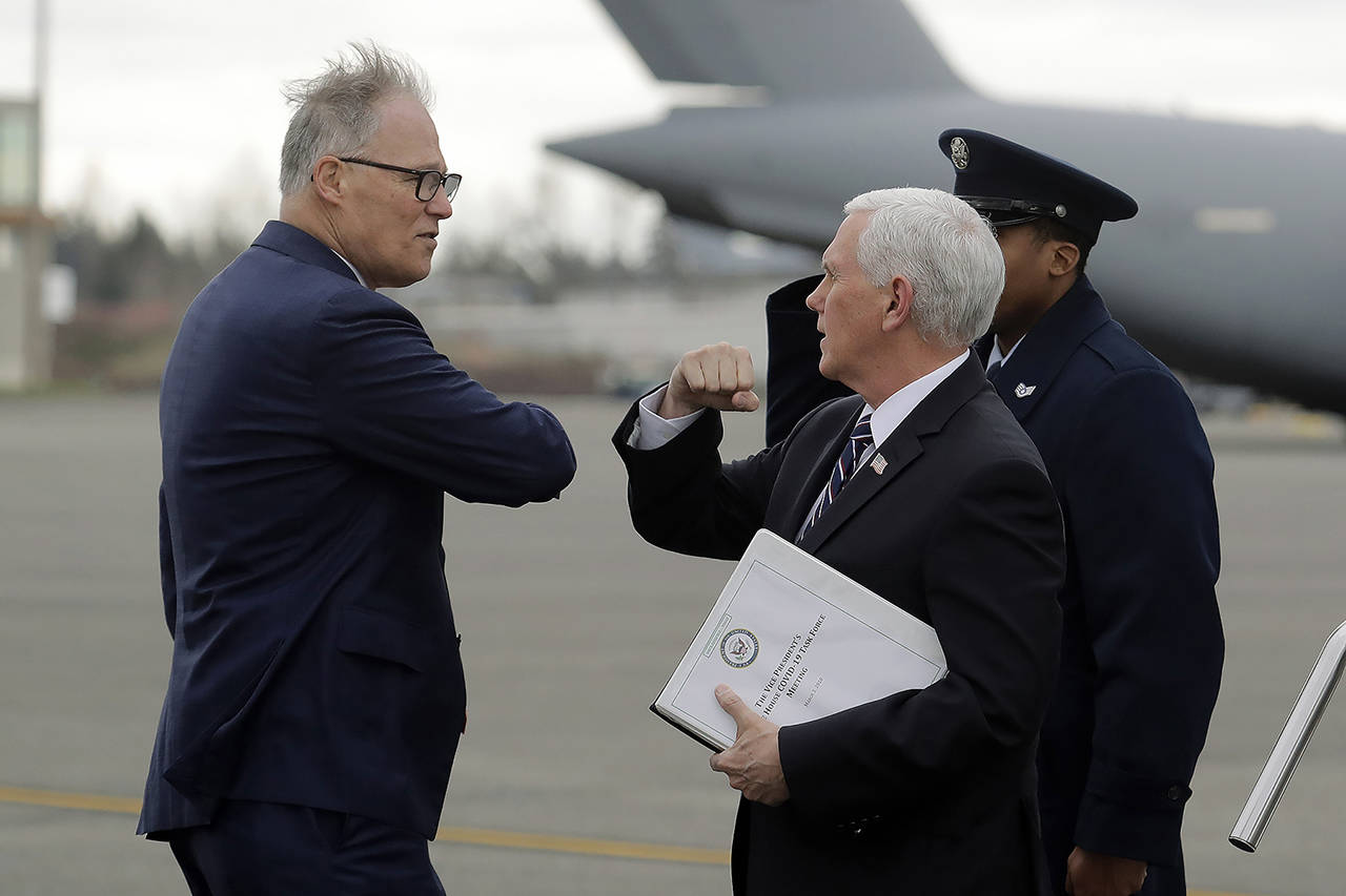Vice President Mike Pence greets Washington Gov. Jay Inslee as Pence arrives Thursday at Joint Base Lewis-McChord. Officials are avoiding handshakes due to the COVID-19 coronavirus. (AP Photo/Ted S. Warren)