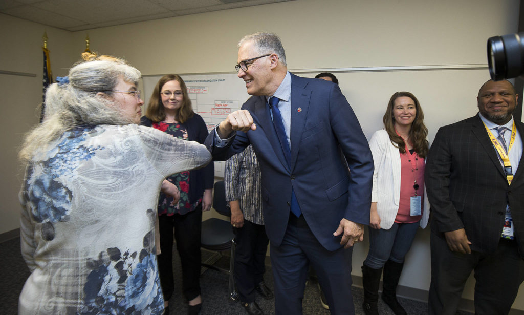 Governor Jay Inslee bumps elbows with staff before a group photo at the Snohomish Health District’s Incident Command Center on Friday in Everett. (Andy Bronson / The Herald)
