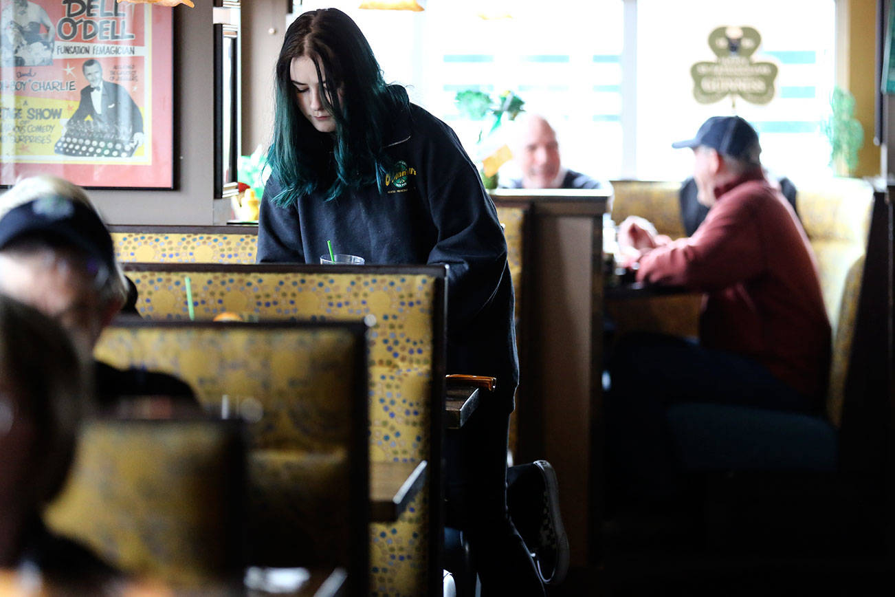 Izzy Sharp clears a table Saturday morning at Shawn O’Donnell’s American Grill and Irish Pub in Everett on March 7, 2020. (Kevin Clark / The Herald)