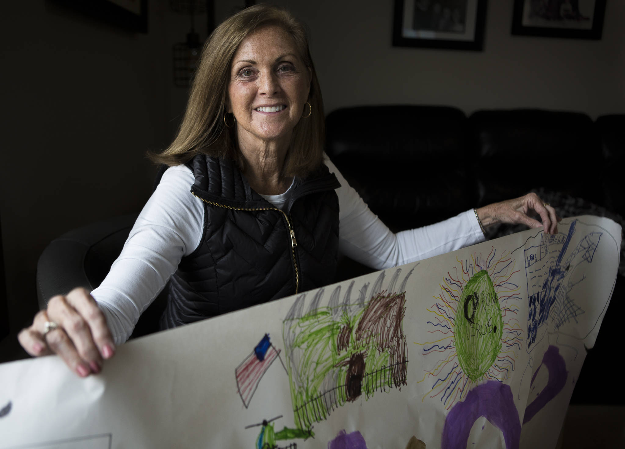 Susan Anabel at her Marysville home with a welcome home sign her grandchildren decorated for her with depictions of the coronavirus, the Diamond Princess cruise ship and the base where she was quarantined. (Olivia Vanni / The Herald)
