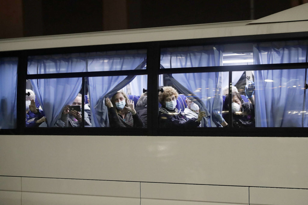 Susan Anabel (center) waves at the media as buses carry her and other passengers from the quarantined Diamond Princess cruise ship at a port in Yokohama, near Tokyo, on Feb. 17. (AP Photo/Jae C. Hong)
