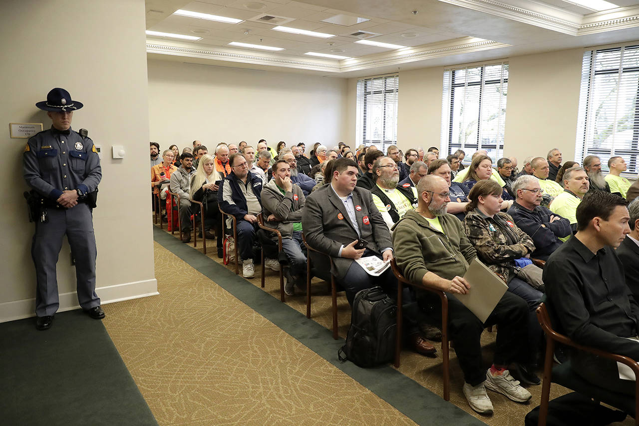 A Washington State Patrol trooper stands watch Feb. 25 as a capacity audience listens to testimony at a public hearing at the Capitol in Olympia on a new bill that would ban high-capacity gun magazines in Washington state. (AP Photo/Ted S. Warren, file)