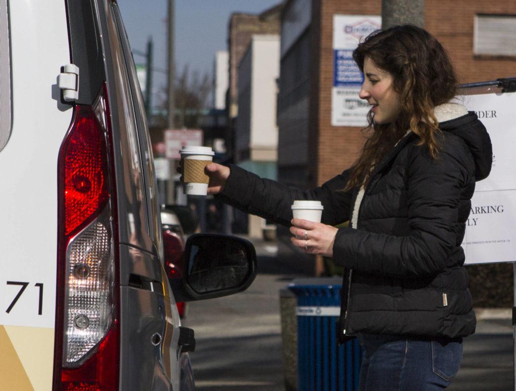 Narrative Coffee employee Eugenia Nestico hands off coffee to customers on Thursday in Everett. (Olivia Vanni / The Herald)
