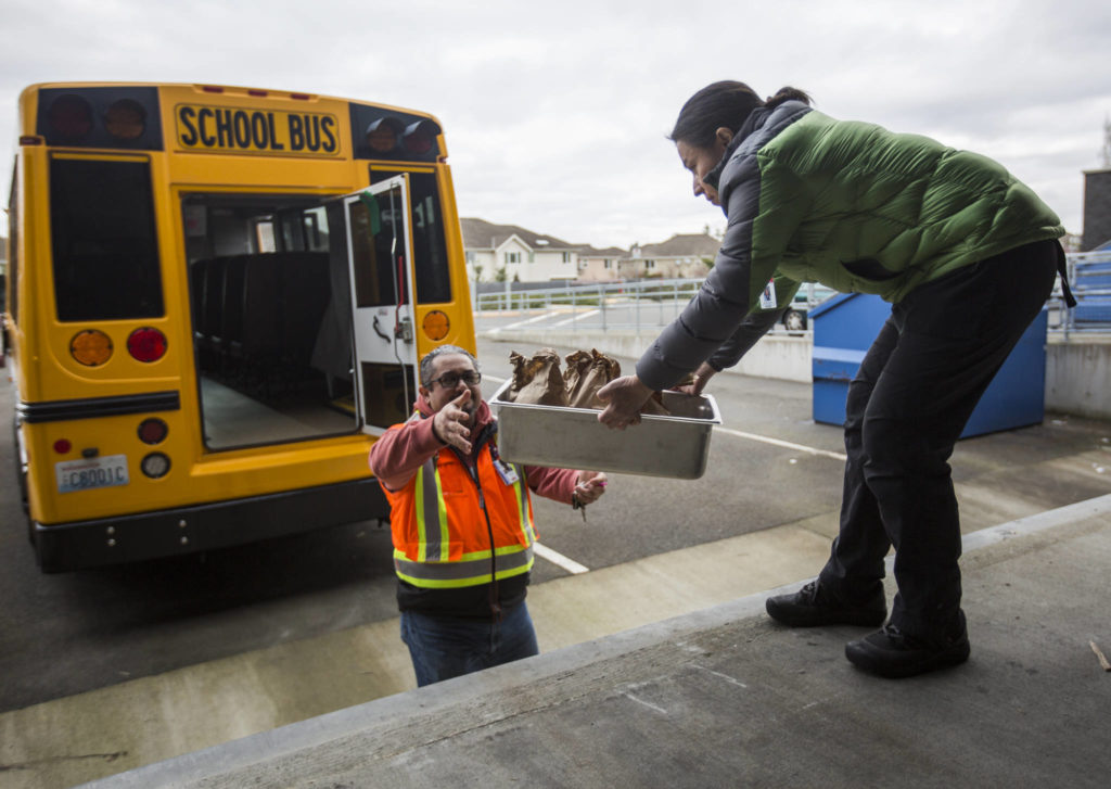 Ileana Koons, right, hands Jorge Rodriguez meals to be delivered to students on Thursday in Bothell. (Olivia Vanni / The Herald)
