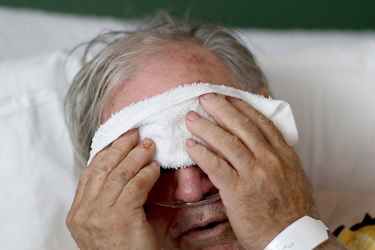A 73-year-old man places a cold compress on his forehead while battling the flu at a hospital in Georgia in 2018. Doctors can test for the flu and get results within a day, but coronavirus testing as of March is still limited in the United States by availability. (David Goldman / Associated Press)