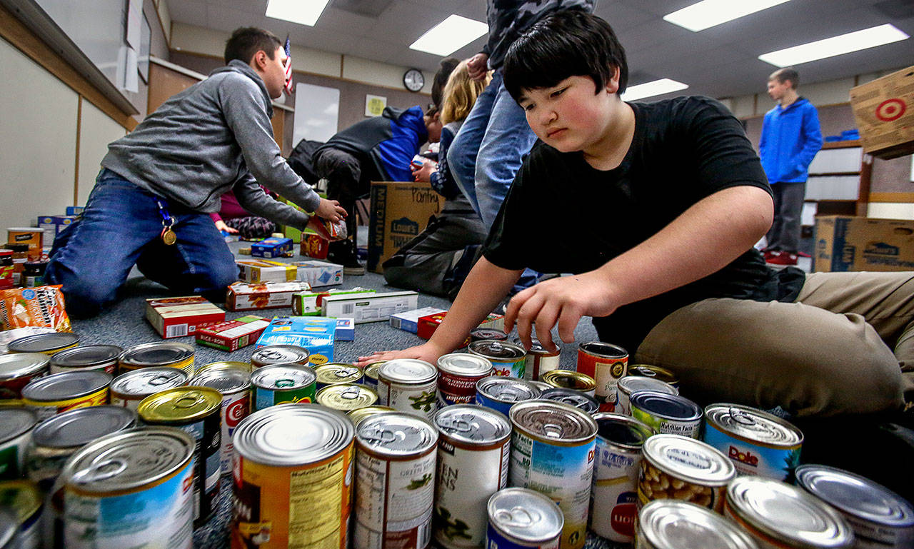 Sixth-grader Jacob Chanthavong sorts canned food and places it in boxes last December at North Middle School in Lake Stevens. His social skills class helped with delivery to the Lake Stevens Community Food Bank. Even amid the Covid-19 outbreak, donations to food banks are an example of the kind of social connections we must continue to make. (Dan Bates / Herald file photo)