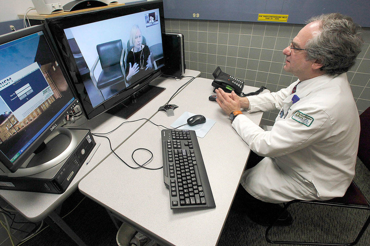 In this 2012 photo, Dr. Terry Rabinowitz (right) talks with nurse Leslie Orelup at Helen Porter Nursing Home in Burlington, Vermont. Doctors have used video feeds and other technology for years to treat patients in remote locations. (AP Photo/Toby Talbot, File)