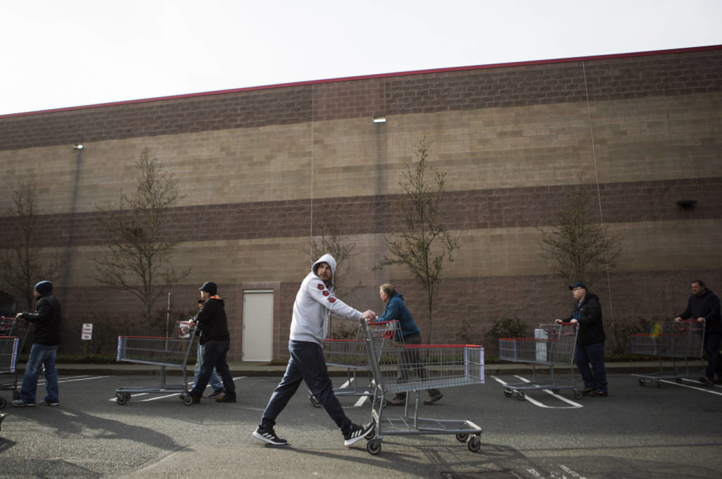 People begin lining up at Costco where the line wrapped around the back of the building on Tuesday in Everett. (Olivia Vanni / The Herald)
