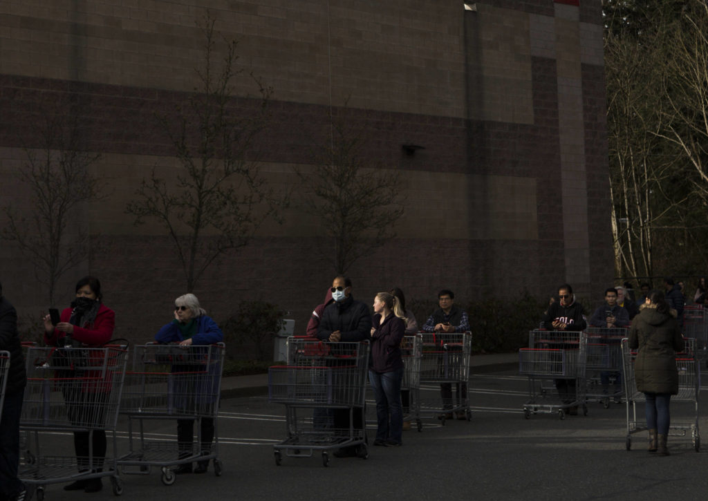 A man stands in line with a mask on Tuesday in Everett. (Olivia Vanni / The Herald)
