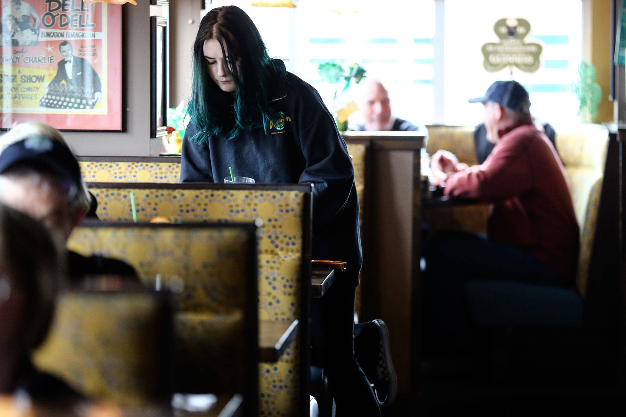 Izzy Sharp clears a table recently at Shawn O’Donnell’s American Grill and Irish Pub in Everett. St. Patrick’s Day, on Tuesday, normally would be like Christmas for the restaurant, with Irish dancers, face painting and folks in leprechaun costumes. This year O’Donnell’s and all other restaurants will be closed, except for takeout service, under order of the governor. (Kevin Clark / The Herald)